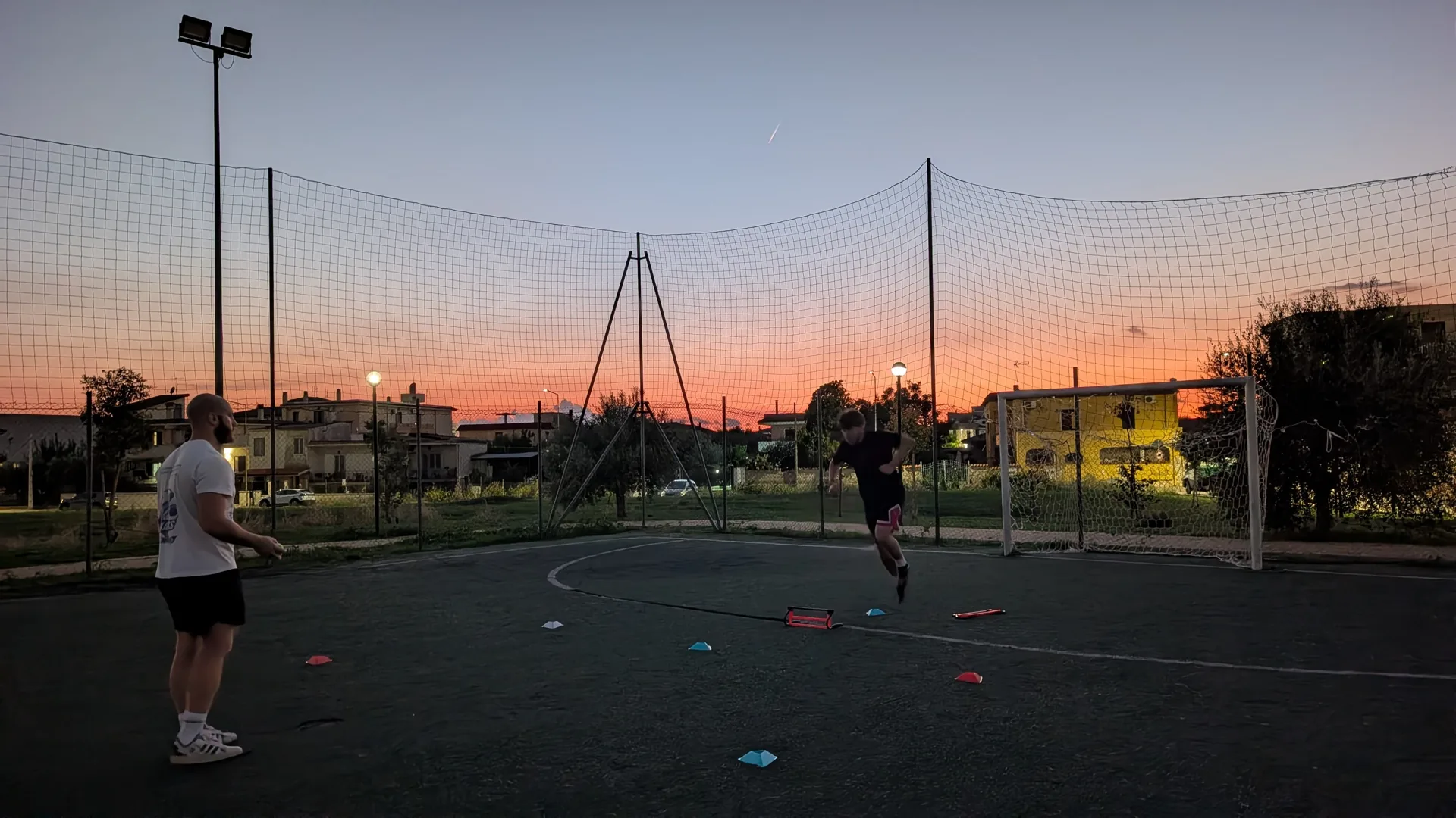 Allenamento di calcio sul campo al tramonto, con un professionista e un atleta